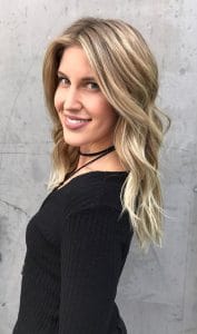 A woman with long blonde hair wearing black.