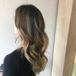 A woman with long hair is standing in front of a wall.