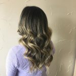 A woman with long hair is standing in front of a wall.