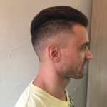 A man with a very short haircut is looking at the wall.