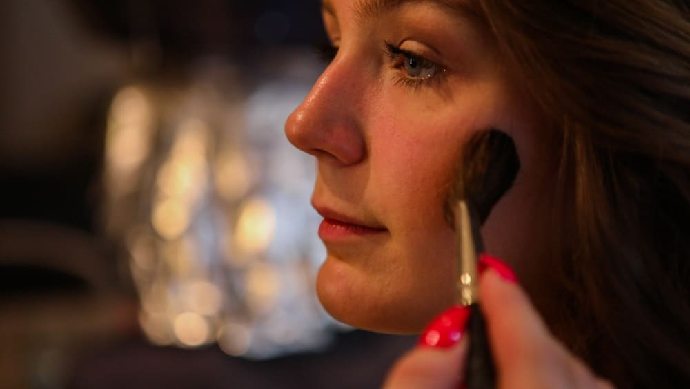 A woman is putting makeup on her face.