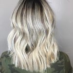 A woman with long blonde hair is wearing a green shirt.