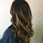 A woman with long hair is standing in front of a wall.