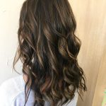 A woman with long hair is standing in front of the wall.