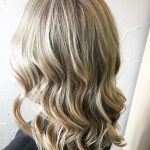 A woman with long blonde hair is looking at the camera.