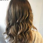 A woman with long hair is standing in front of a wall.