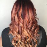 A woman with long red hair is looking at the camera.