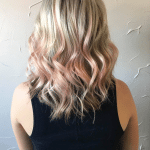 A woman with long blonde hair and pink highlights.