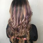 A woman with long hair is standing in front of a wall.