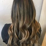 A woman with long hair is standing in front of a wall.