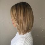 A woman with long hair is wearing white and has blonde highlights.