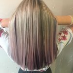 A woman with long blonde hair is standing.