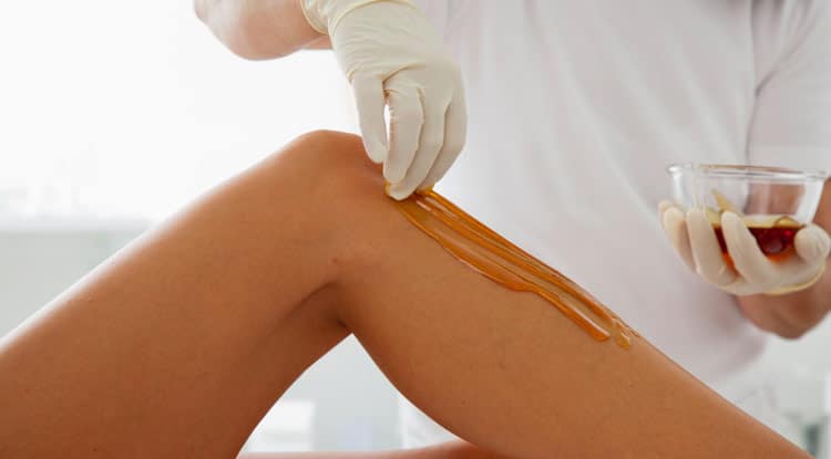 A person is waxing their legs with wax applicator.