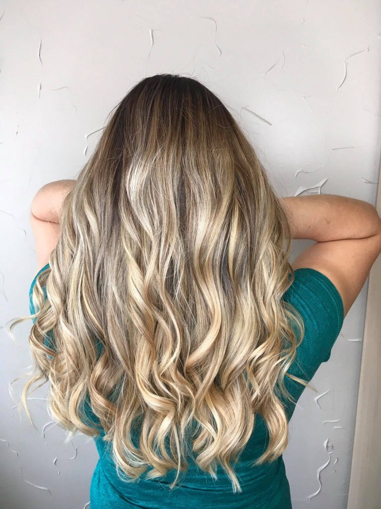 A woman with long blonde hair is standing against the wall.