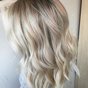 A woman with long blonde hair is standing in front of a door.