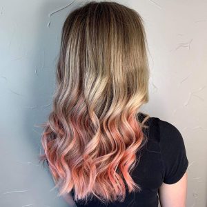 A woman with long blonde hair and pink highlights.