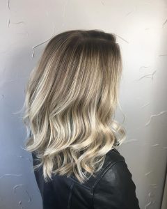 A woman with long blonde hair in front of a wall.
