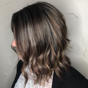A woman with long hair is standing in front of a wall.