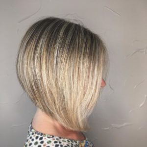 A blonde woman with short hair is wearing a dress.