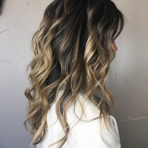A woman with long hair is standing in front of a wall.