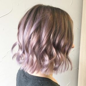 A woman with purple hair is looking at the wall.