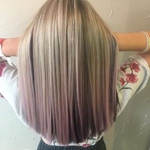 A woman with long blonde hair is standing.