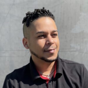 A man with a black shirt and red necklace.