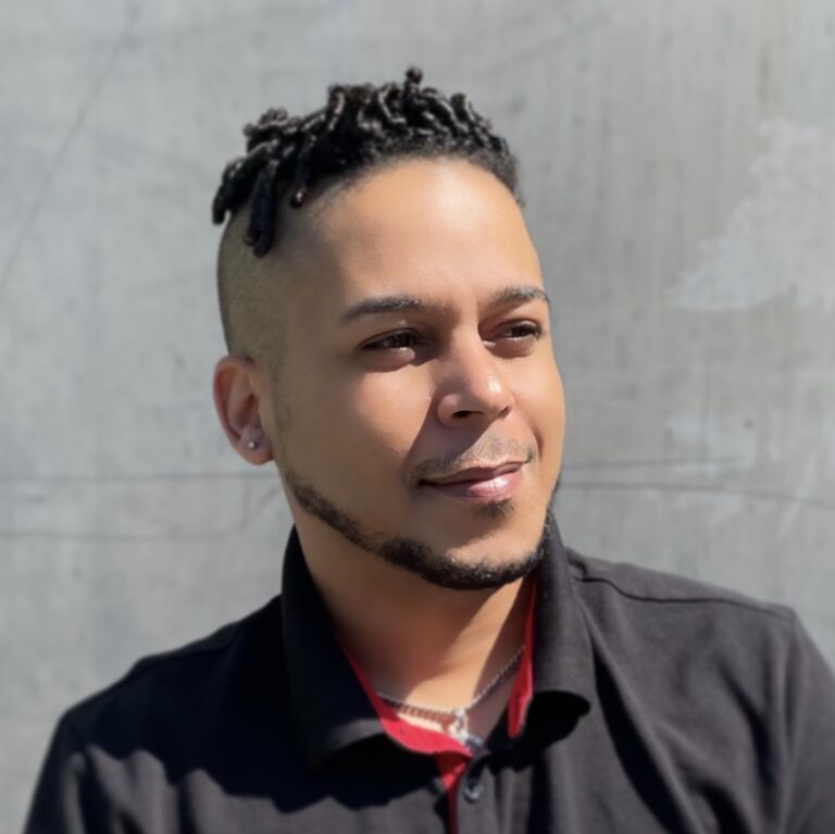 A man with a black shirt and red necklace.