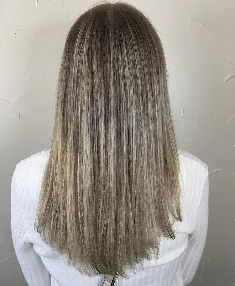 A woman with long hair is standing in front of the wall.