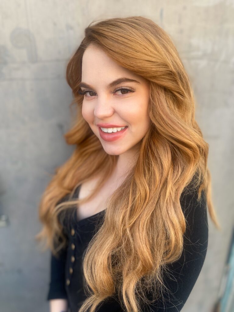 A woman with long blonde hair smiling for the camera.